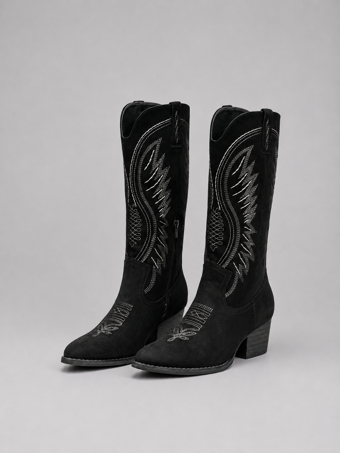 Black cowboy boots with detailed embroidery on a gray background