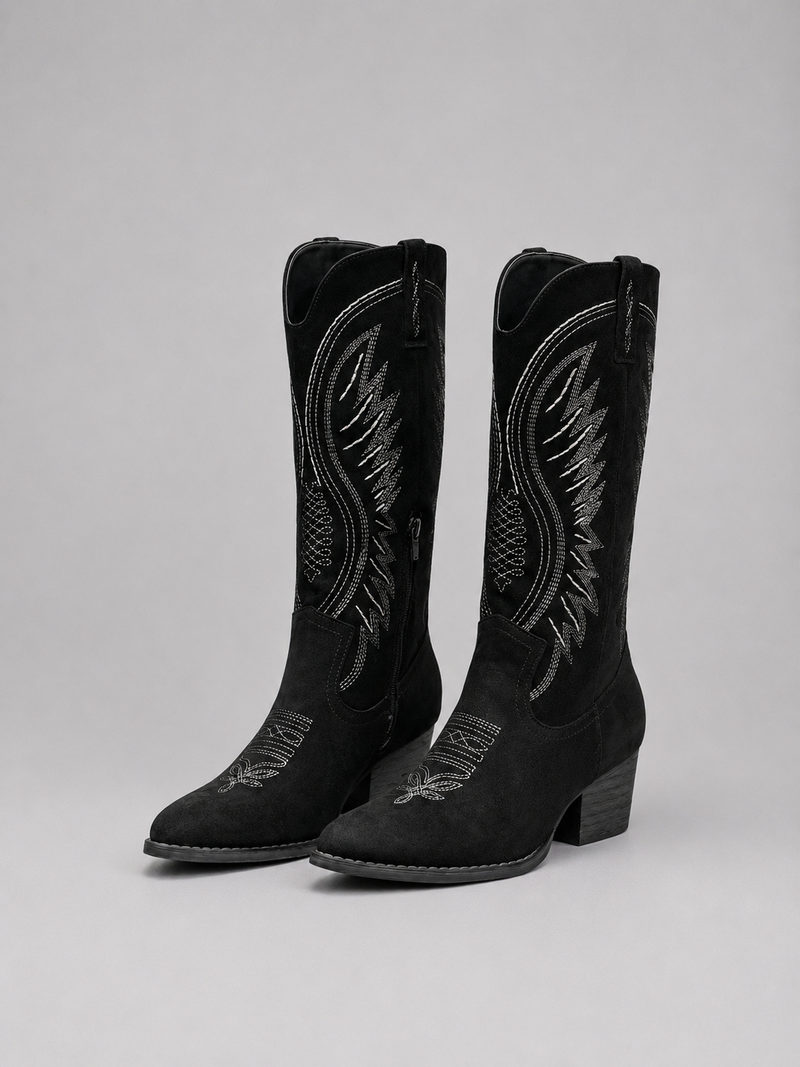 Black cowboy boots with detailed embroidery on a gray background