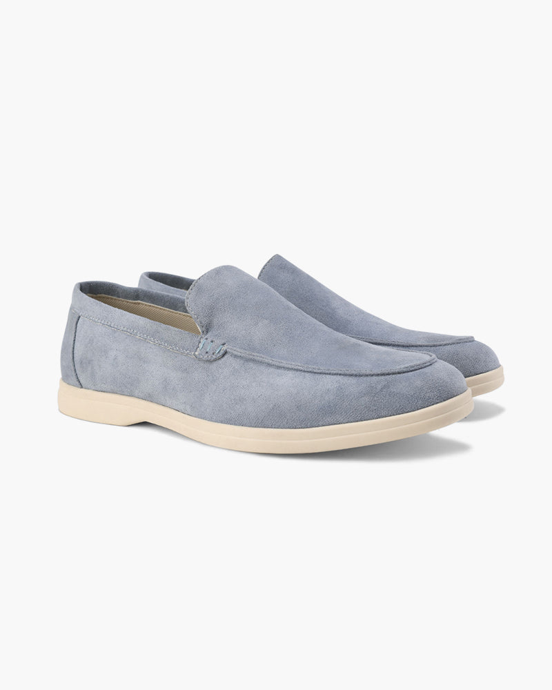 Pair of light blue suede loafers on a white background