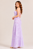Woman wearing a strapless lavender gown against a plain background
