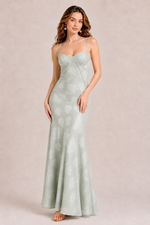Woman wearing a light green evening gown against a beige background