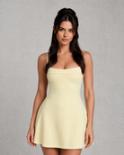 Woman wearing a light yellow dress against a gray background