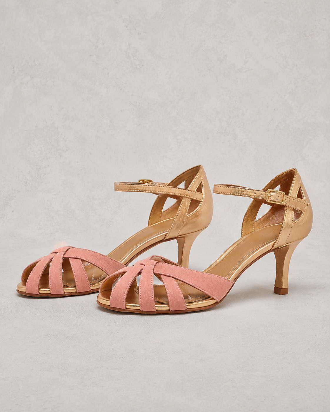 Pair of pink and beige strappy sandals on a light gray background