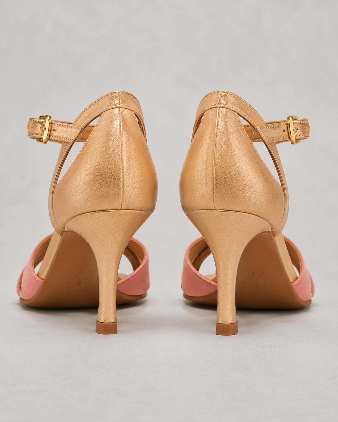 Pair of tan high-heeled shoes with pink soles on a gray background
