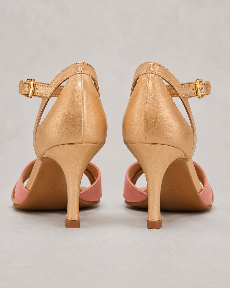 Pair of tan high-heeled shoes with pink soles on a gray background