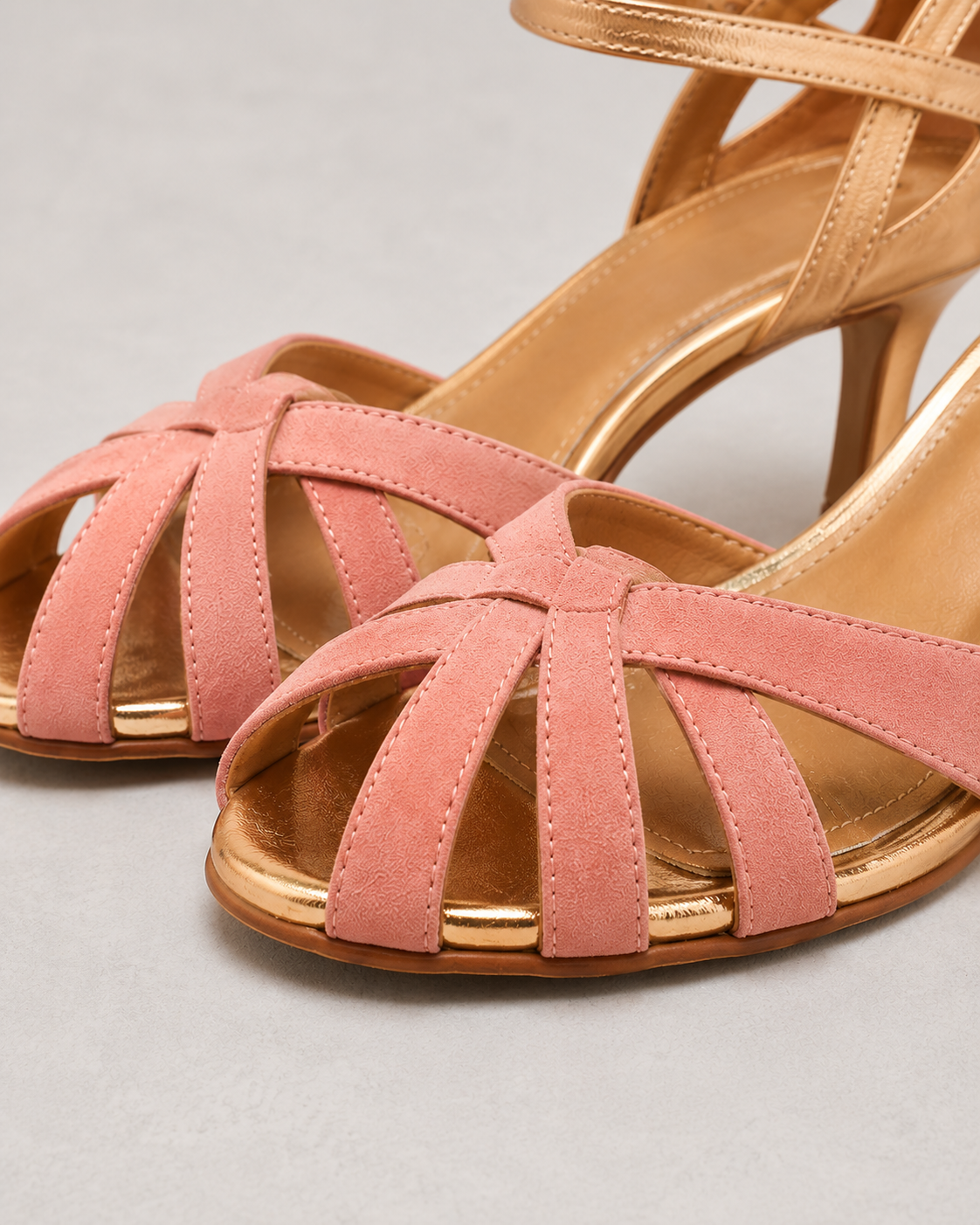 Pair of pink strappy sandals on a light gray background