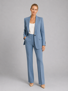 Woman wearing a light blue suit with a white top on a gray background