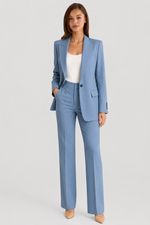 Woman wearing a light blue suit with a white top on a gray background