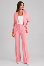 Woman wearing a pink suit with a white top on a gray background