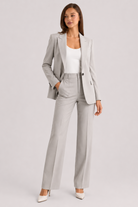 Woman wearing a gray suit with a white top on a light gray background