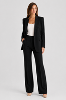 Woman wearing a black suit with a white top on a light gray background