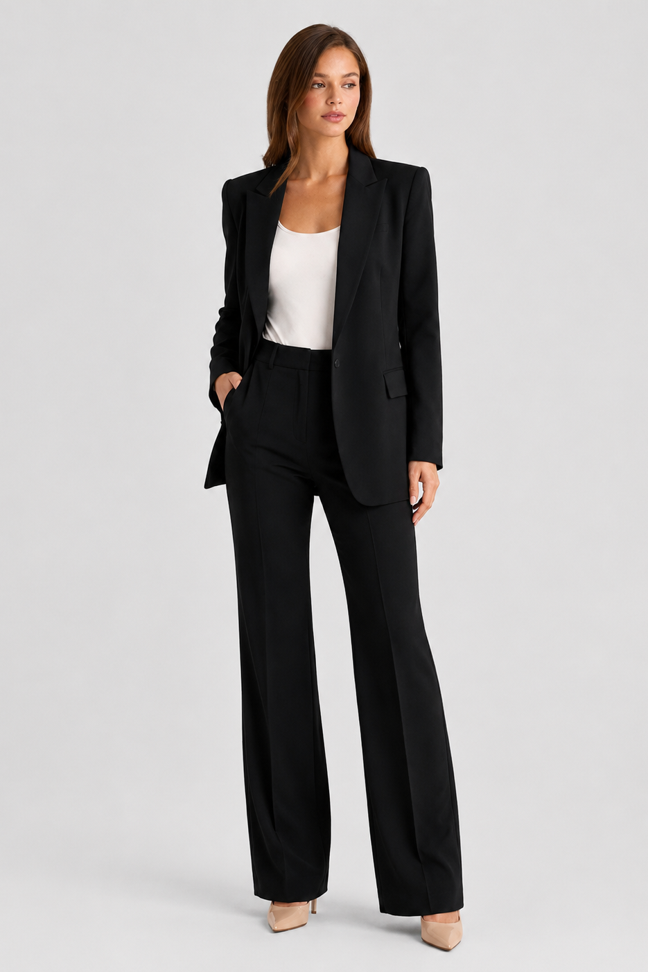 Woman wearing a black suit with a white top on a light gray background