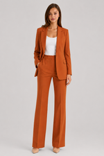 Woman wearing a rust-colored suit with a white top on a light gray background