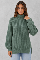 Woman wearing a green knitted sweater against a gray background