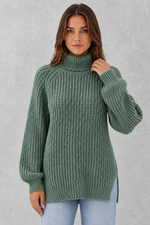 Woman wearing a green knitted sweater against a gray background