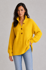 Woman wearing a yellow sweater with brown buttons against a gray background
