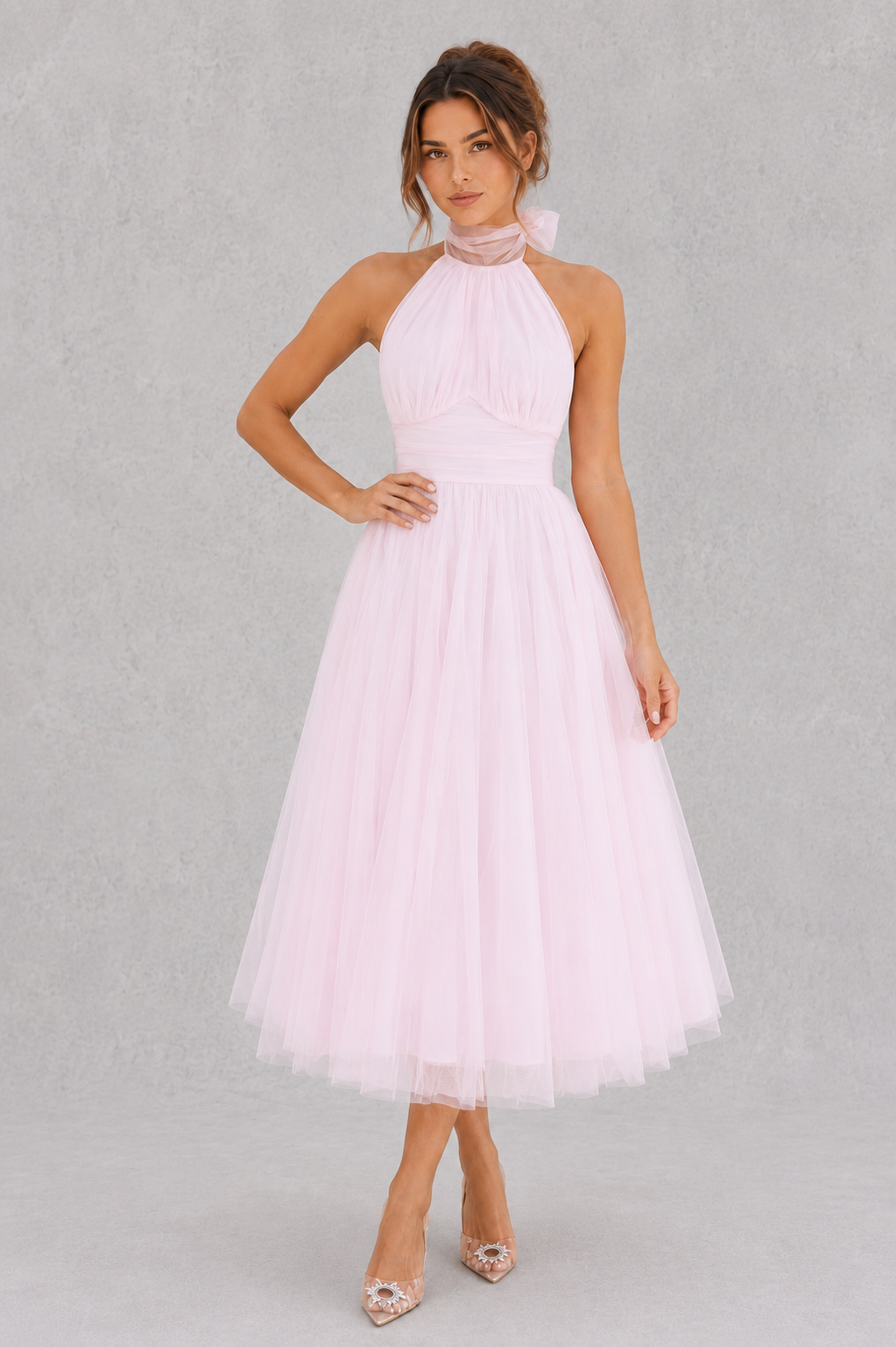 Woman wearing a light pink halter neck dress on a gray background