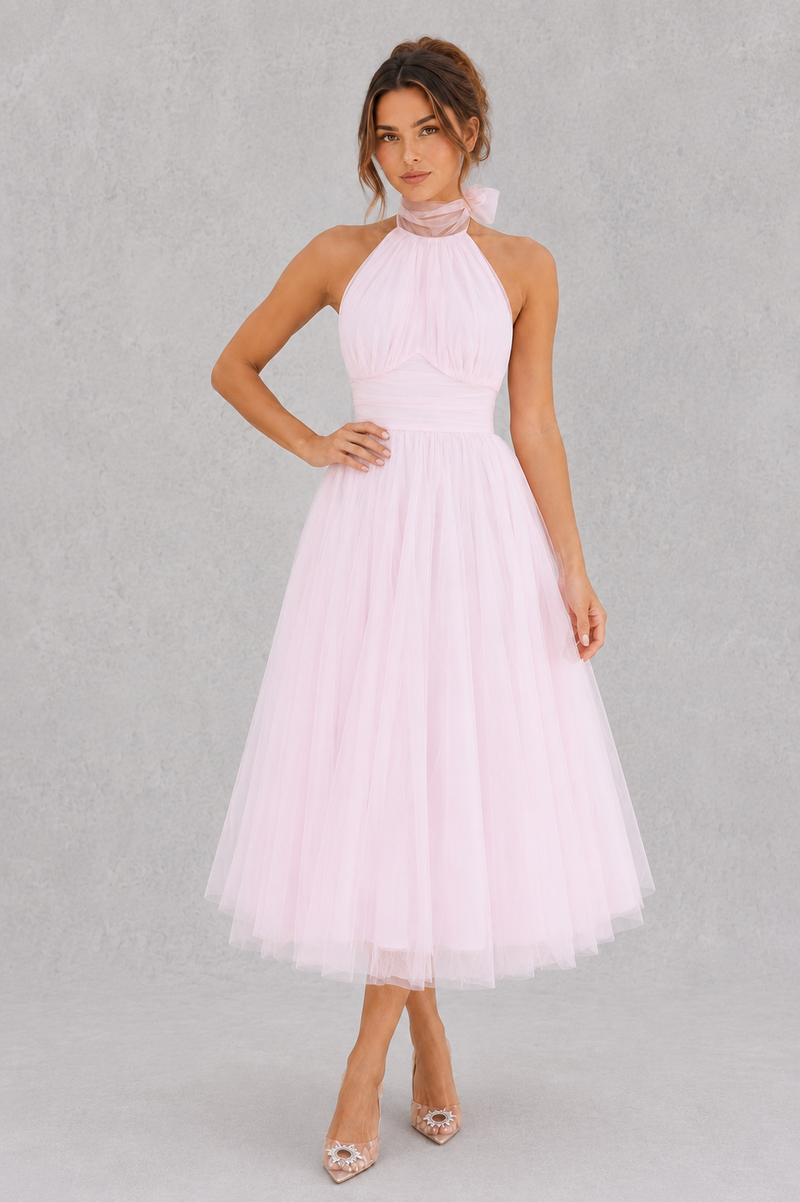 Woman wearing a light pink halter neck dress on a gray background