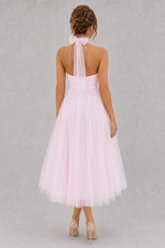 Woman wearing a light pink dress with a sheer halter top on a gray background