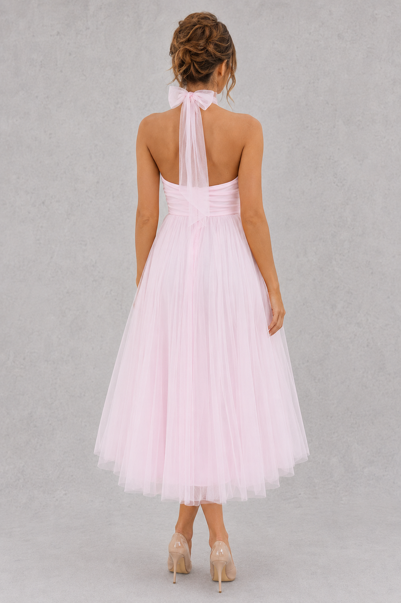 Woman wearing a light pink dress with a sheer halter top on a gray background