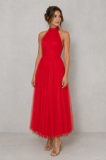Woman wearing a red halter neck dress against a plain background