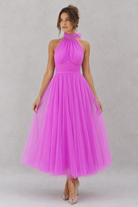 Woman wearing a pink dress against a gray background