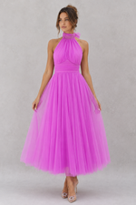 Woman wearing a pink dress against a gray background