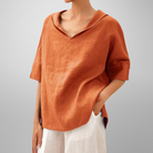 Person wearing an orange linen shirt with a plain background