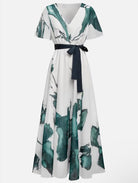 White dress with green leaf pattern and black belt on a white background