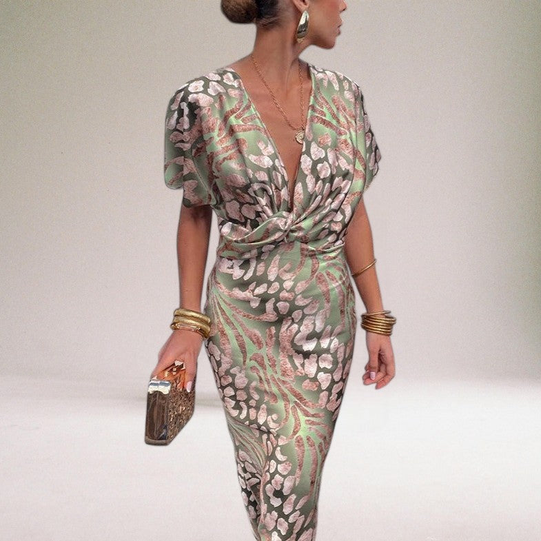 Woman wearing a patterned jumpsuit with gold accessories on a plain background