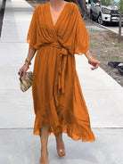 Woman wearing an orange dress on a sidewalk with a blurred background