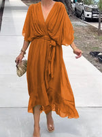 Woman wearing an orange dress on a sidewalk with a blurred background