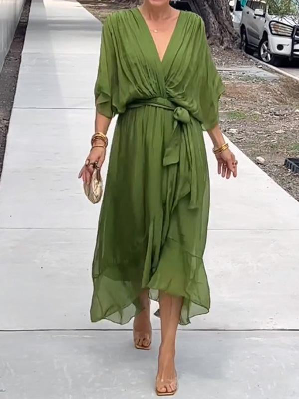 Woman wearing a green dress on a white pathway.