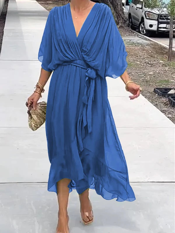 Woman wearing a blue dress standing on a sidewalk.
