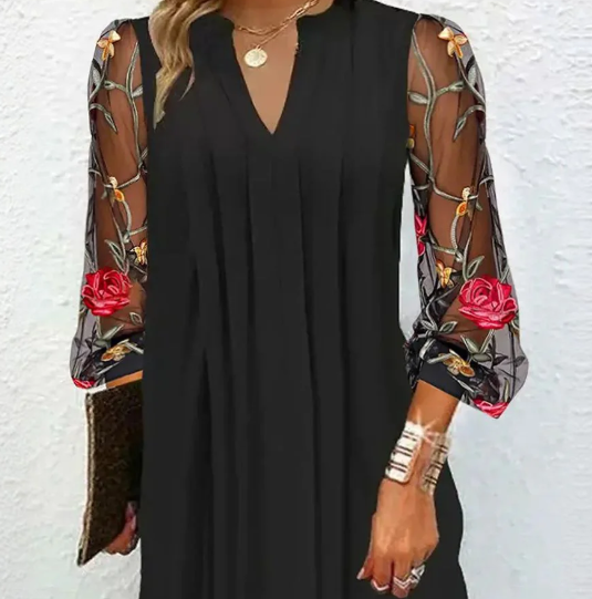 Black dress with floral sheer sleeves on a textured white background