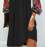 Person wearing a black dress with floral sleeves against a light background