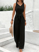 Woman wearing a black sleeveless jumpsuit standing on stone steps.
