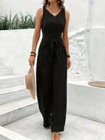 Woman wearing a black sleeveless jumpsuit standing on stone steps.