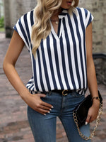 Woman wearing a navy and white striped top with blue jeans, holding a black handbag.