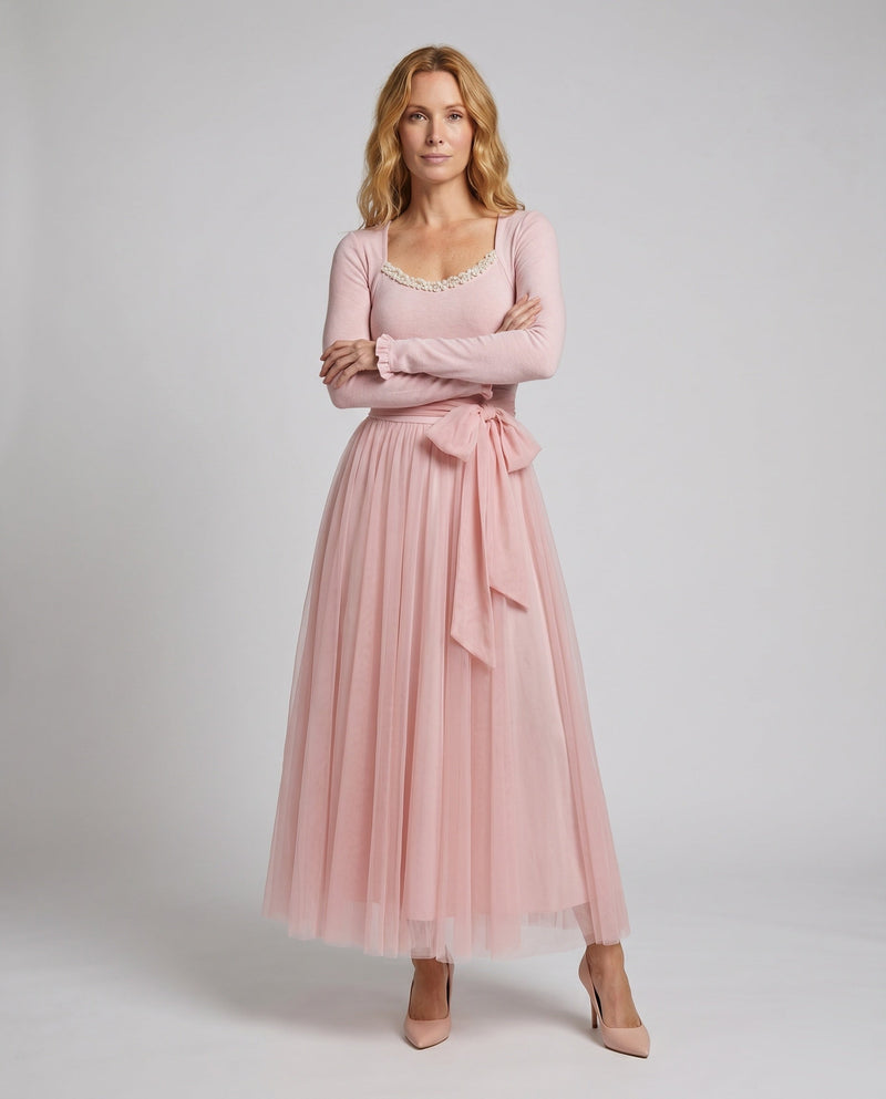 Woman wearing a pink dress with a matching cardigan on a white background