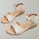 Pair of beige sandals with cork wedge sole on a light gray background