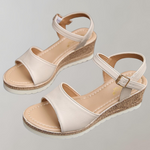 Pair of beige sandals with cork wedge sole on a light gray background