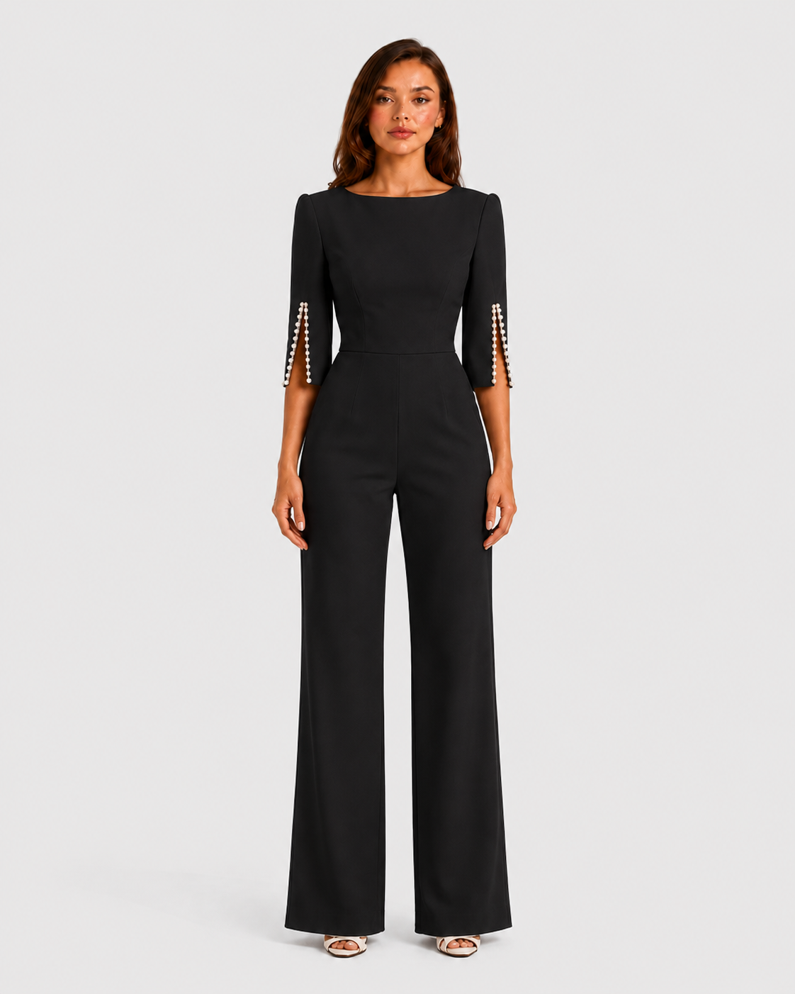 Woman wearing a black jumpsuit with metallic cuffs on a white background