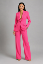 Woman wearing a bright pink suit against a gray background