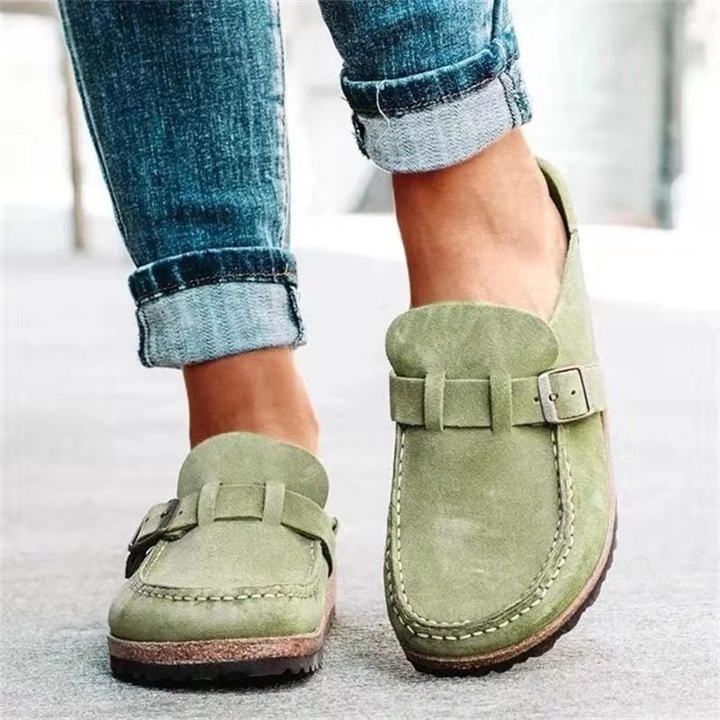 Green suede loafers worn with rolled-up jeans on a light background
