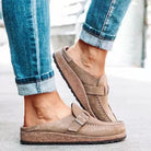 Brown sandals worn with rolled-up blue jeans on a light background