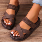 Brown sandals with braided straps on a wooden floor