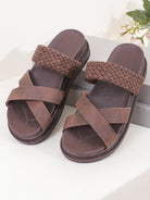 Pair of brown sandals with woven straps on a white surface.